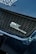A close-up view of a car's front grille featuring the logo SWK Suzuki Works Kurume. The grille has a honeycomb pattern, and the surrounding areas of the car are a glossy blue color with visible reflections.
