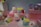 A collection of cute, colorful plush toys is displayed on a set of pink platforms. The toys have large, expressive eyes and resemble popular cartoon characters. Around the toys, there are small, colorful blocks, adding to the vibrant aesthetic.
