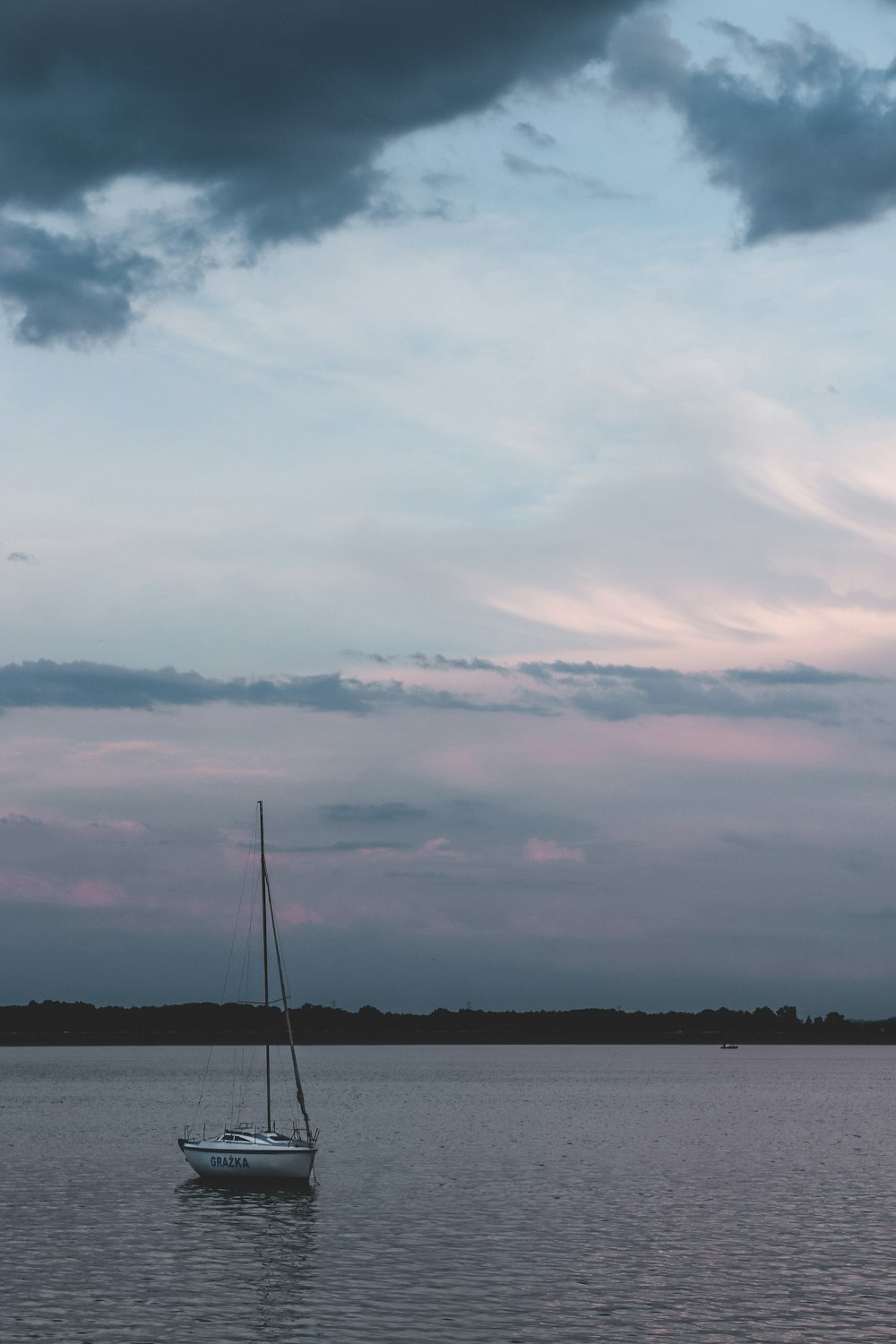 a sailboat floating on a lake under a cloudy sky