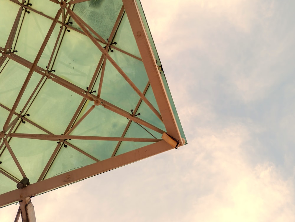 a glass and metal structure against a cloudy sky