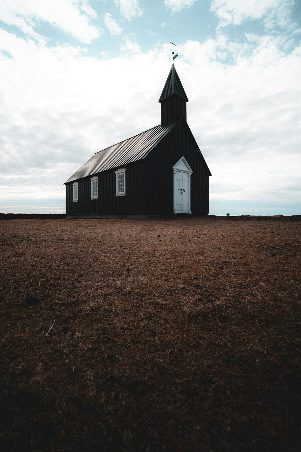 a black church with a steeple and a white door