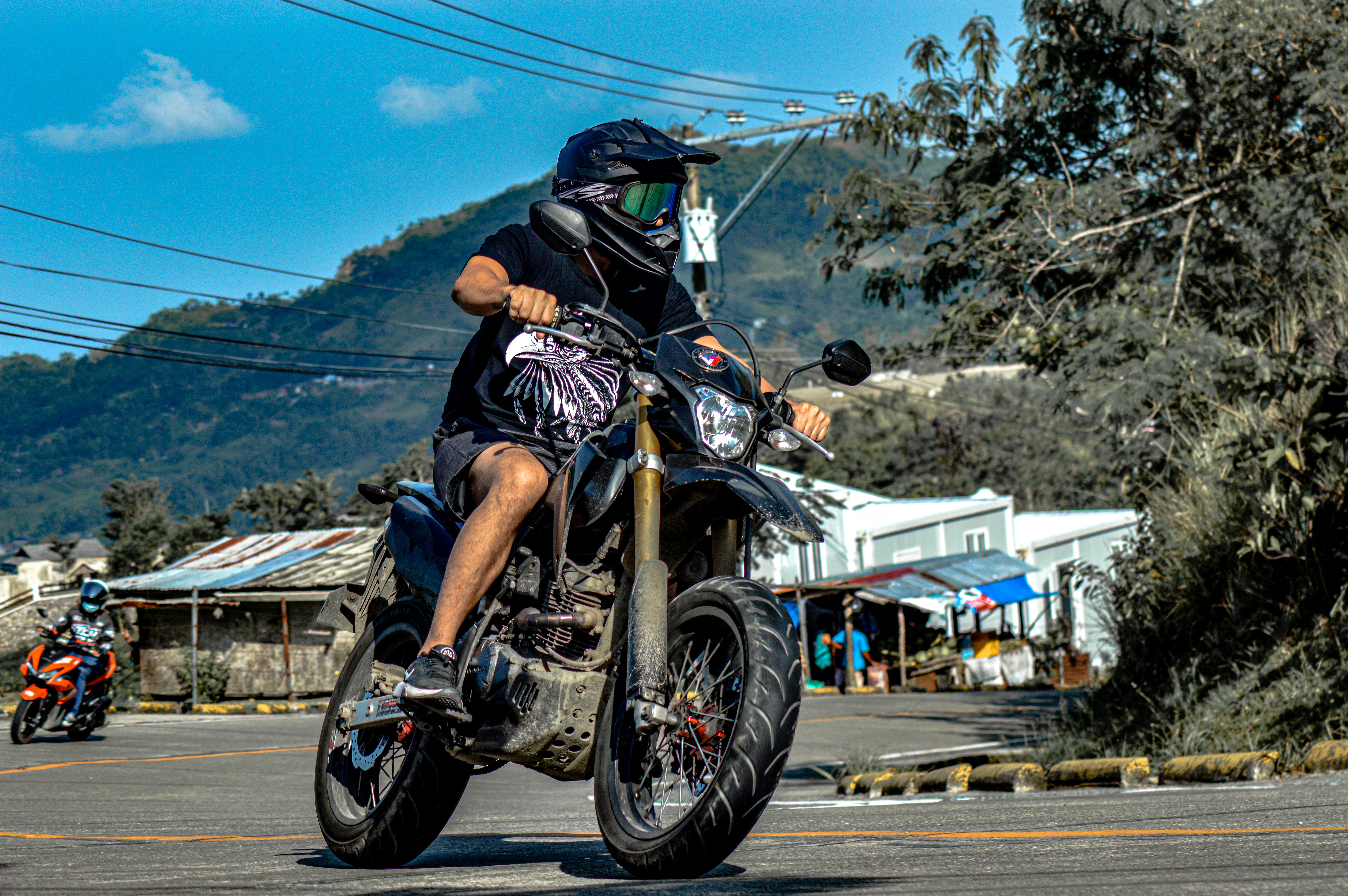 A man riding a motorcycle down a street photo – Free Vacation Image on ...