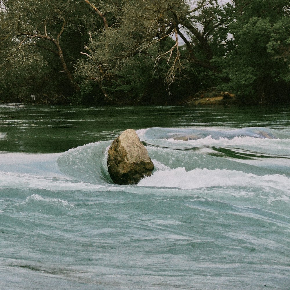 a large rock sitting in the middle of a river