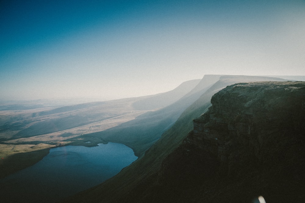 a person standing on top of a mountain next to a lake