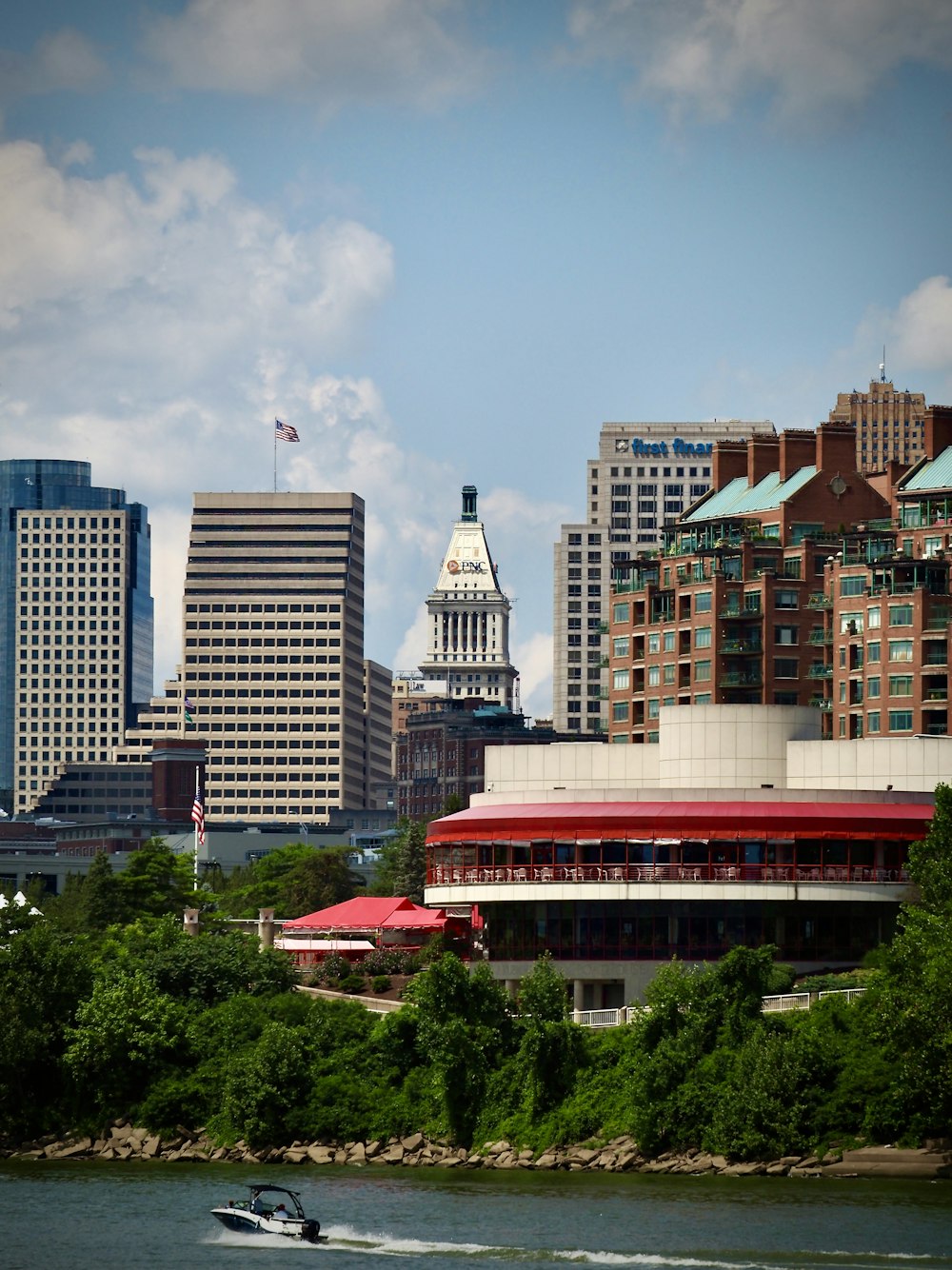 a boat traveling down a river past tall buildings