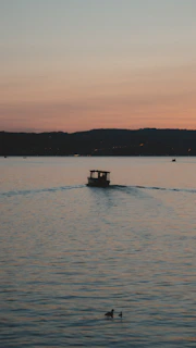A serene figure in a boat glides across calm waters under a twilight sky, symbolizing transition and hope.