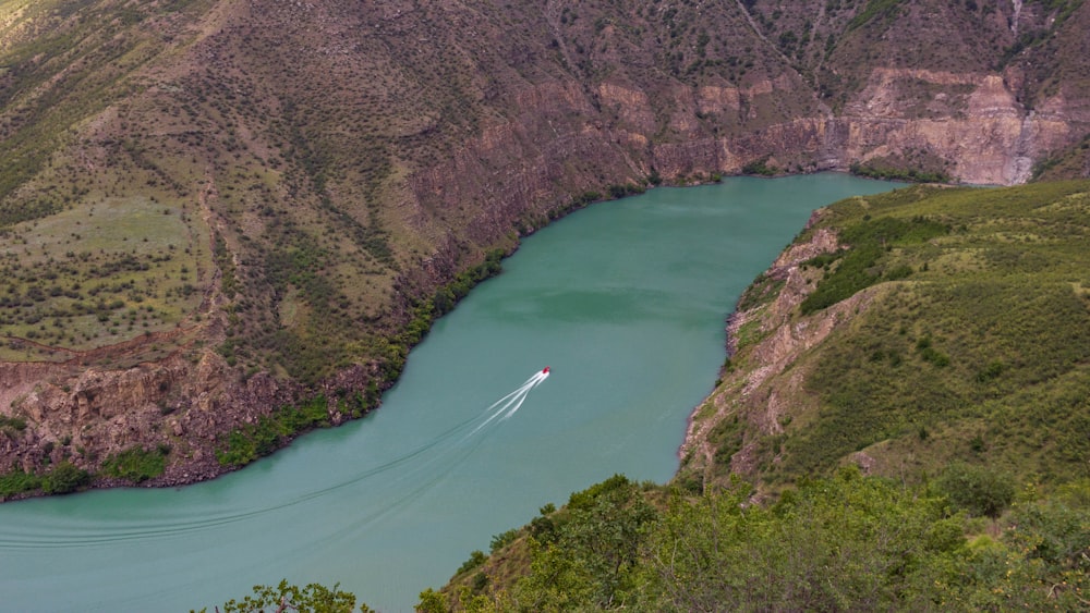 a boat traveling down a river surrounded by mountains