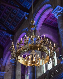 Close-up of a technician carefully installing a grand chandelier with royal blue accents.