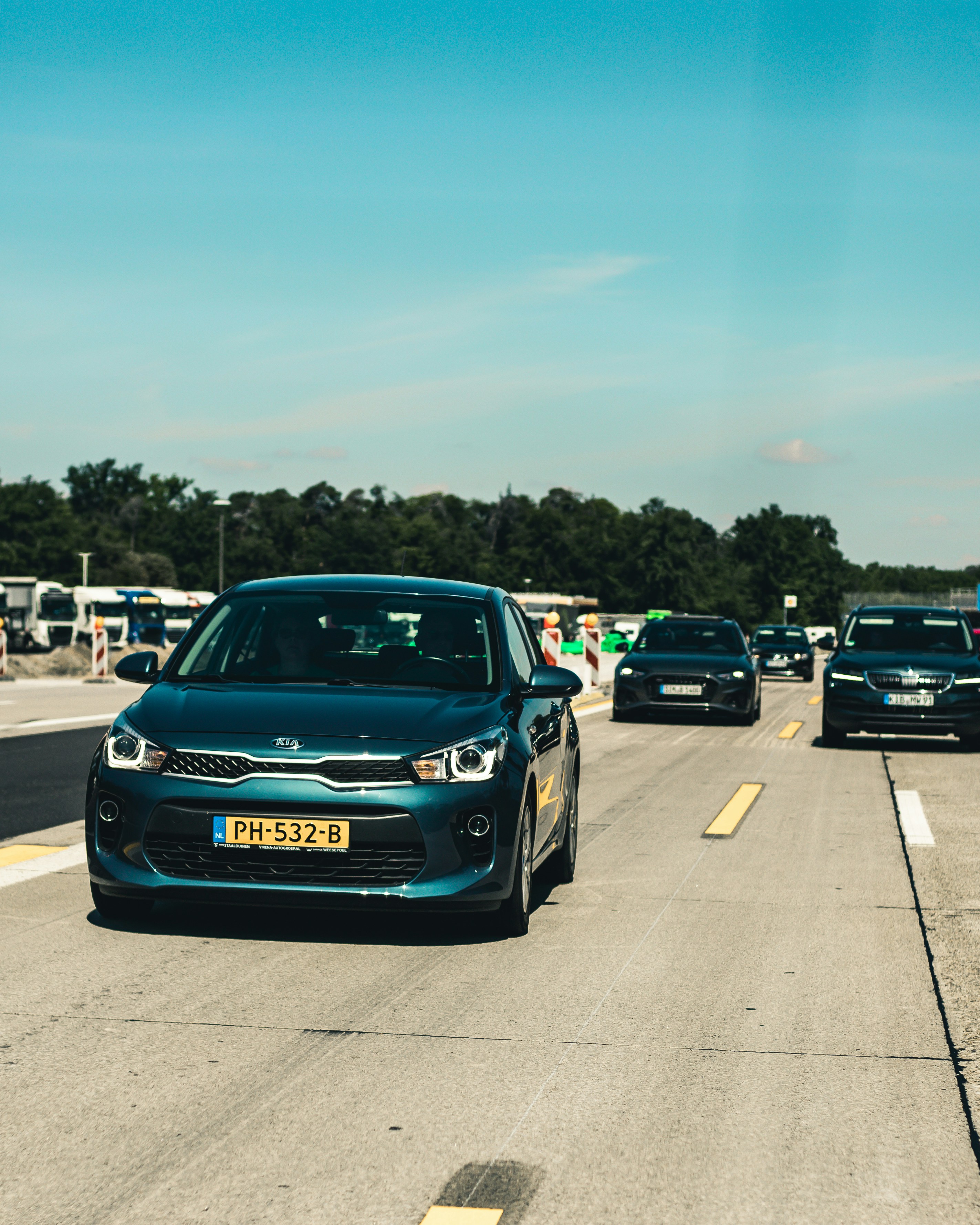 Blue Kia K5 sedan on a sunny road