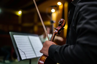 A smiling young student holding a violin in a cozy living room setting.