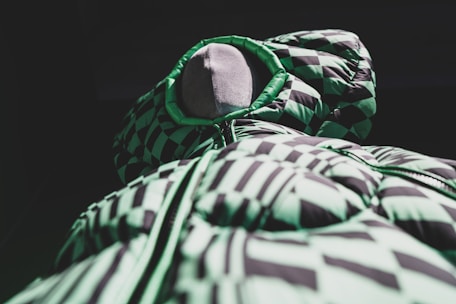 A stylish garment displayed on a mannequin in a softly lit studio with green accents.