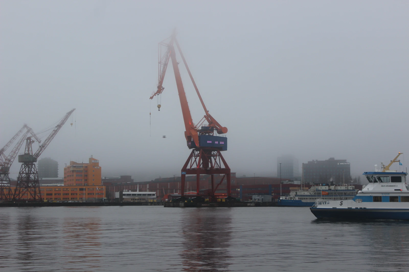 Harbor crane and ferry in morning fog