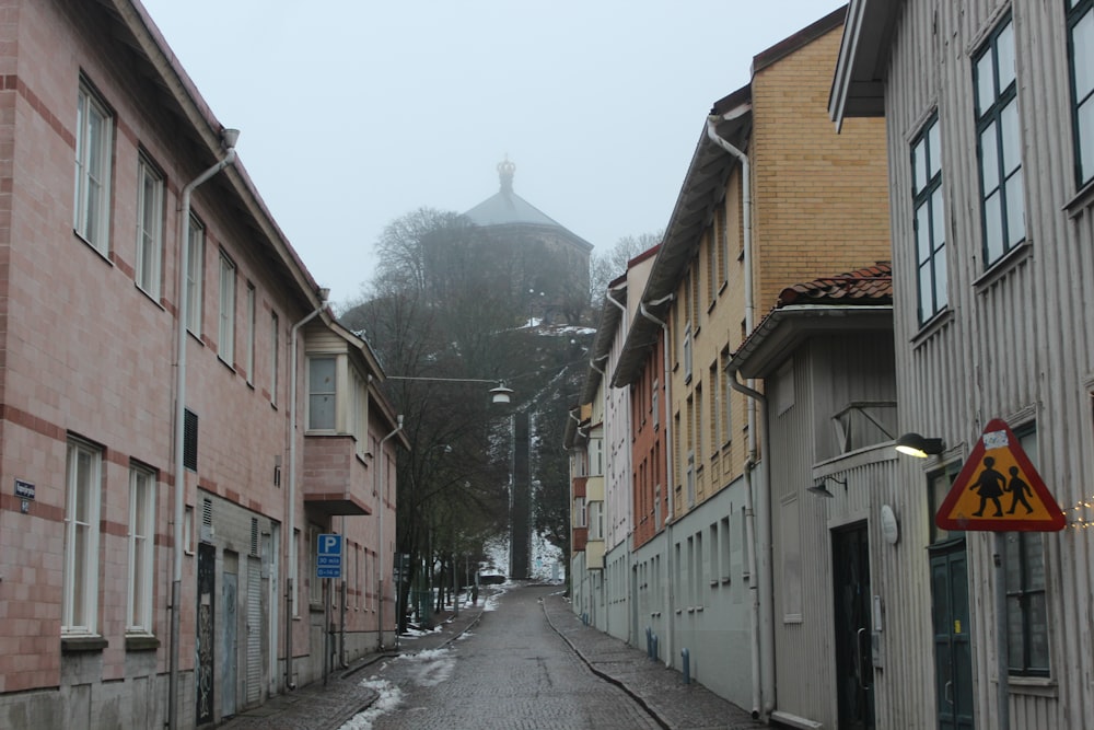 a narrow street with buildings and a steeple in the background