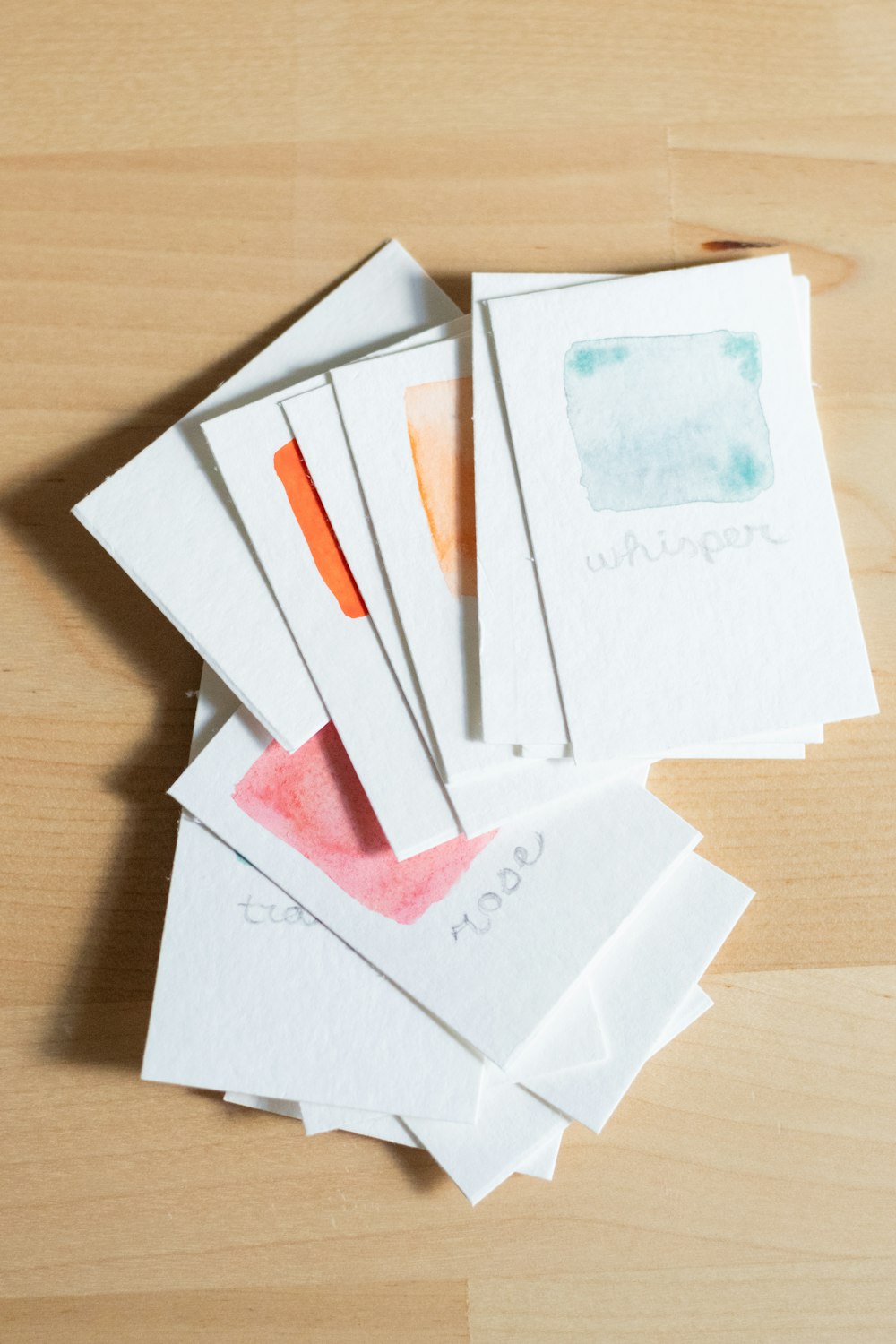 a pile of watercolor papers sitting on top of a wooden table