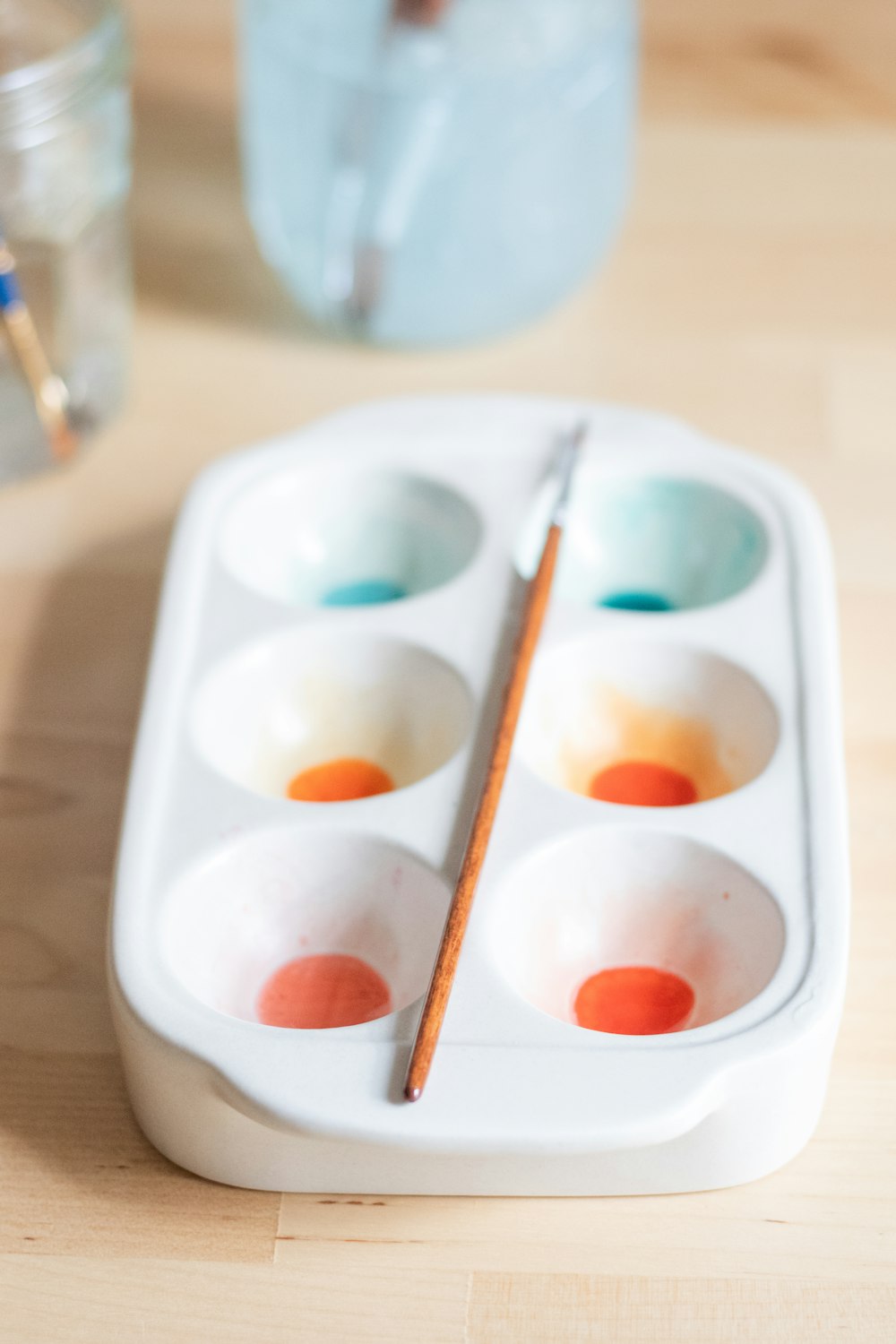 a paint palette with a pair of chopsticks in it