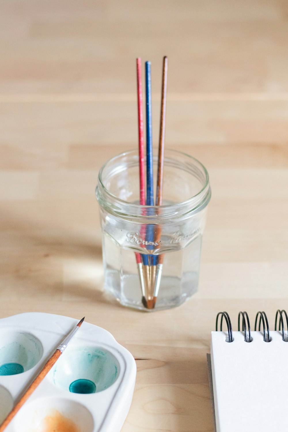 a jar of paint and two brushes on a table