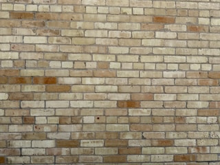 Photo of a freshly built brick wall with clean mortar lines under natural daylight.