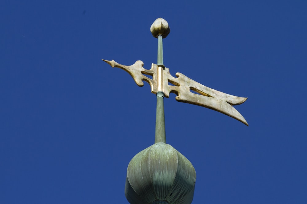 a weather vane on top of a building with a blue sky in the background