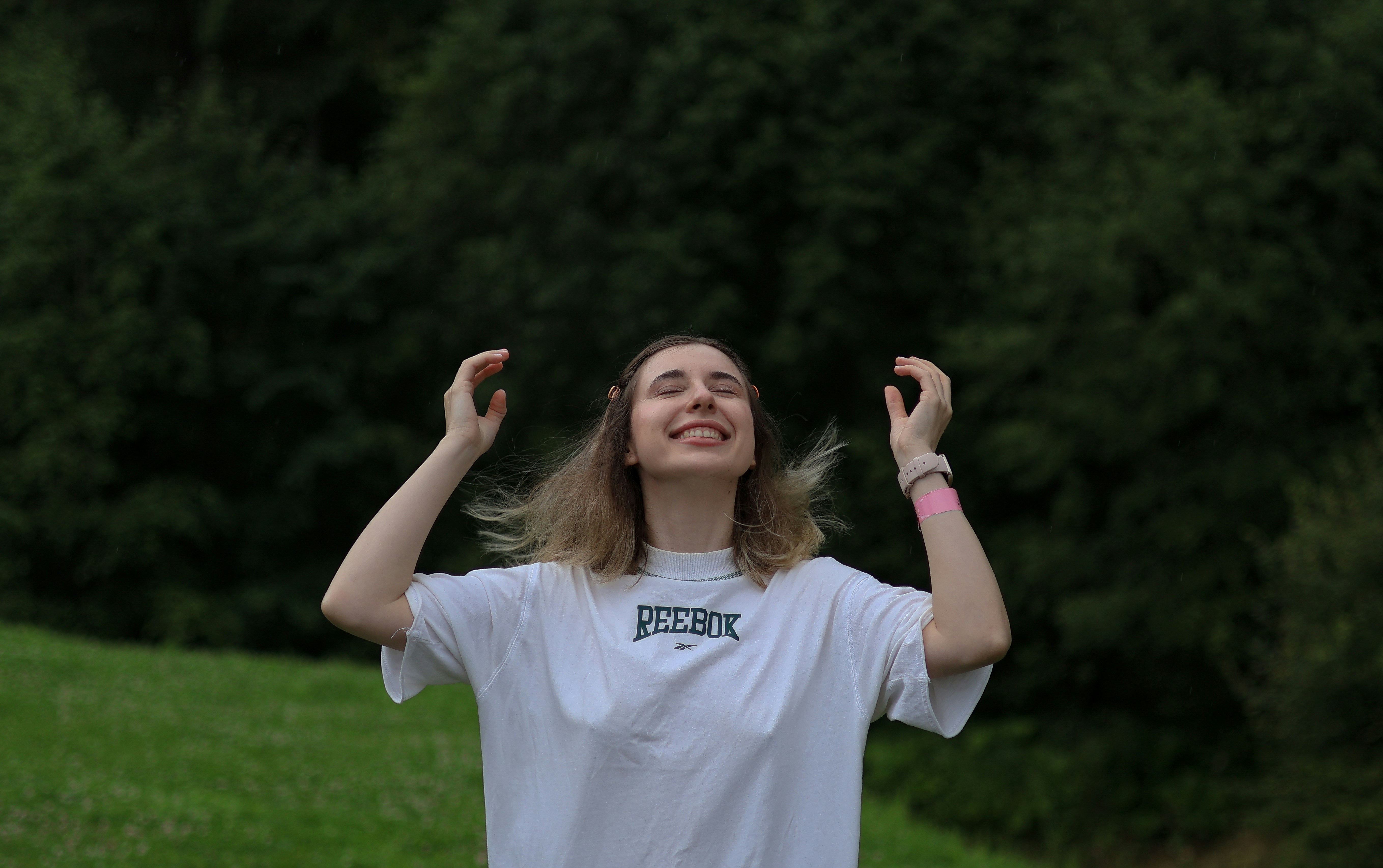 a woman standing in a field with her hands in the air