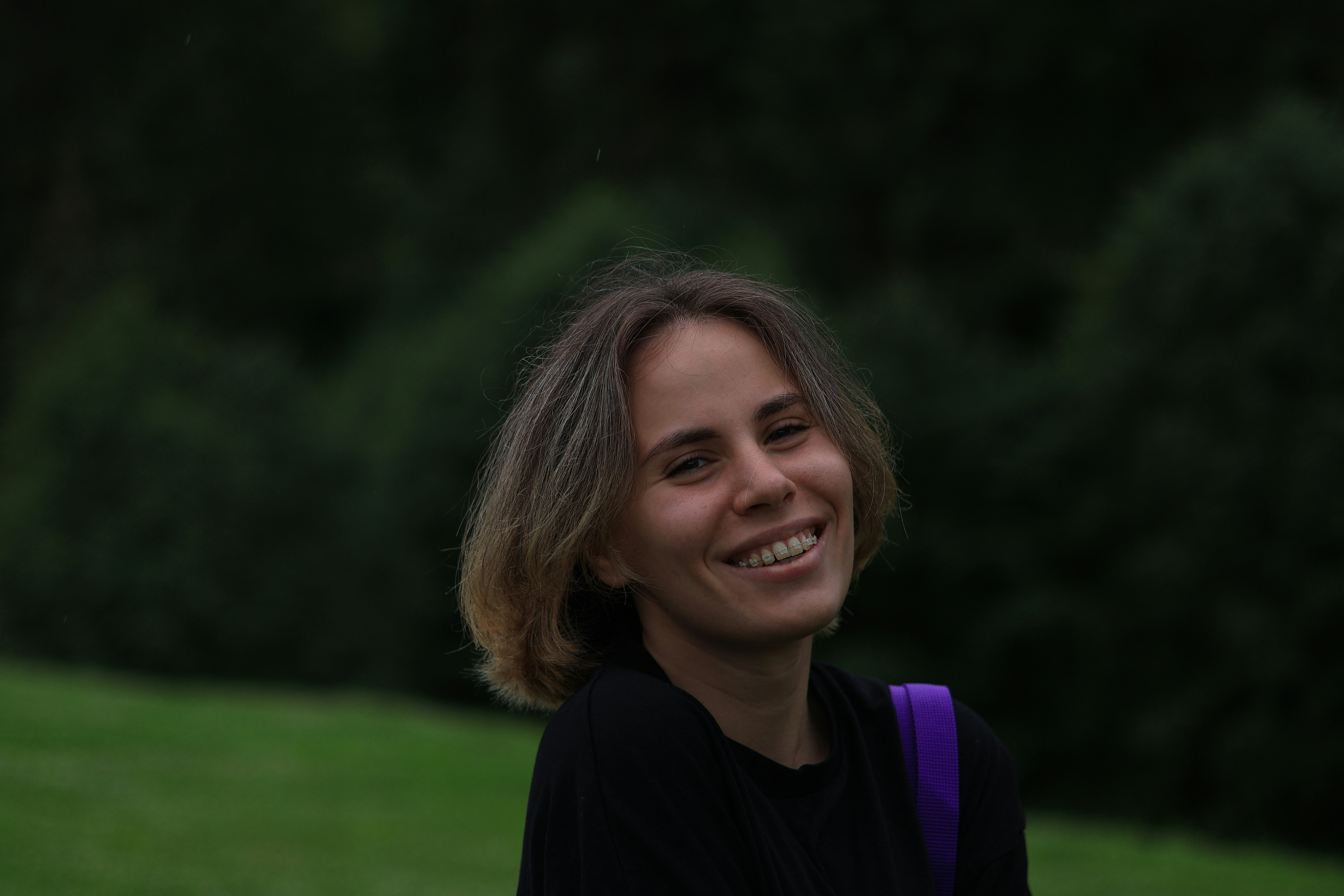 a woman with a purple backpack smiles at the camera