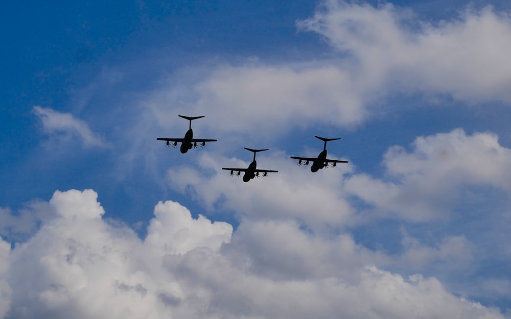 a group of three airplanes flying through a cloudy sky