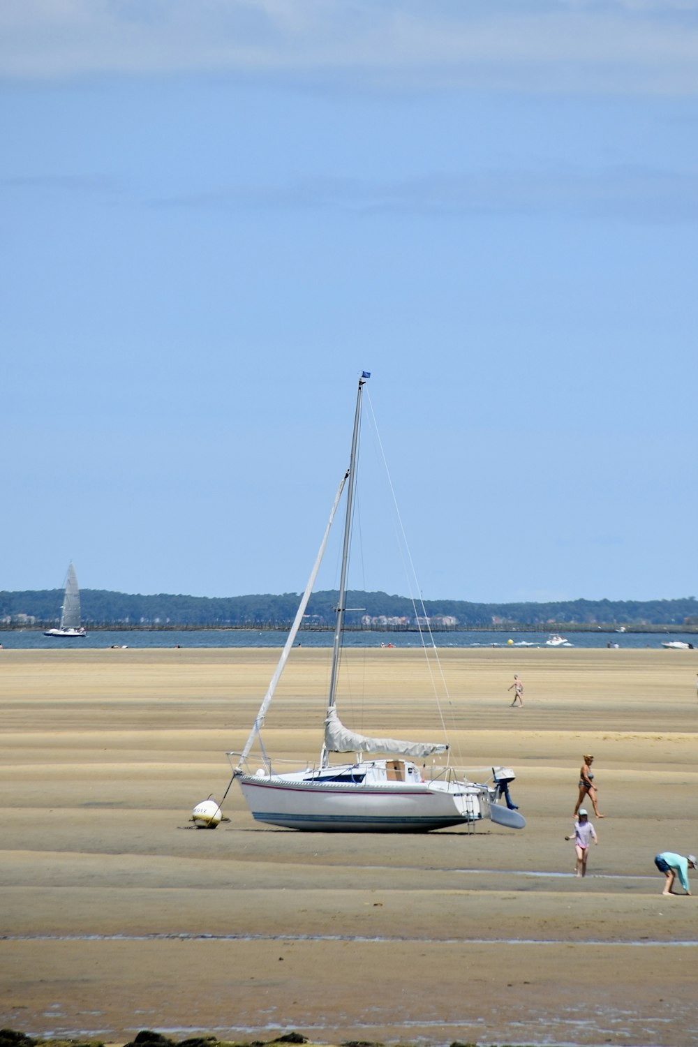 un voilier sur la plage avec des gens debout autour