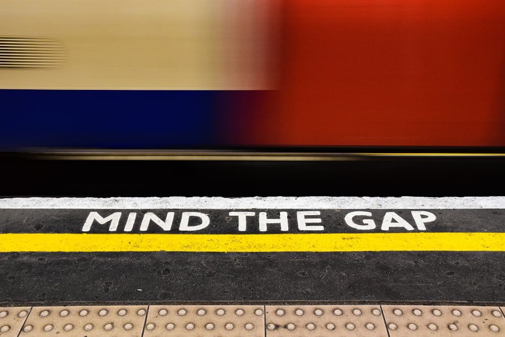 a train passing by a sign that says mind the gap