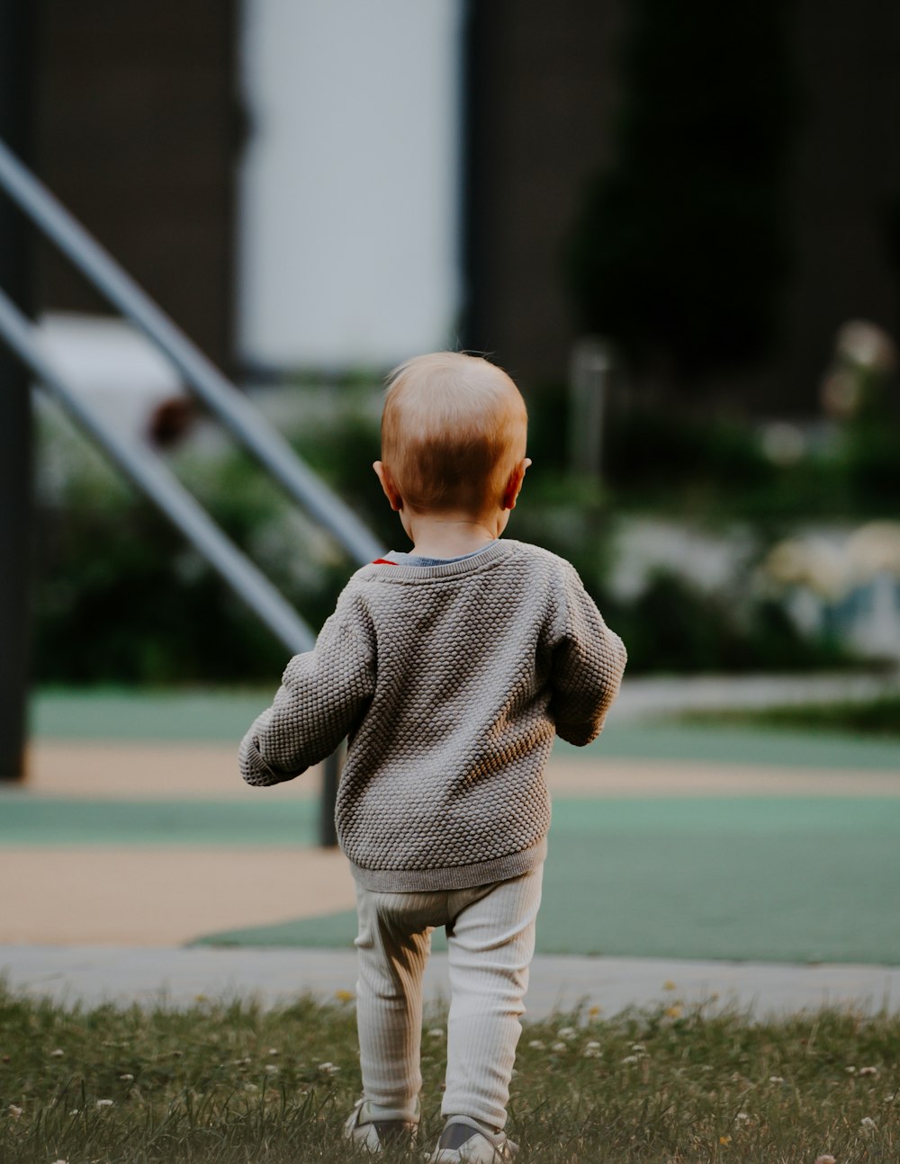 a little boy running in the grass with a kite in the background