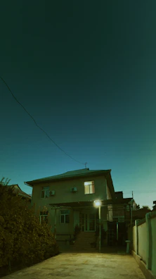 Image showing an electrician installing outdoor lighting on a house facade at dusk.
