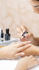 a woman is doing a manicure on a child's hand