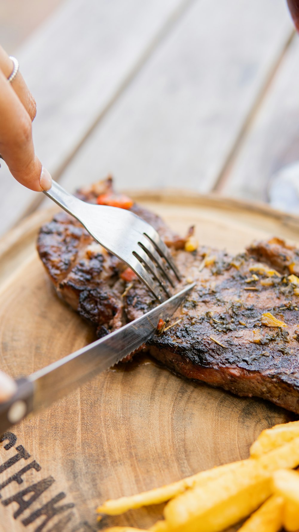 a person cutting a piece of steak with a fork and knife