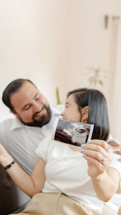 a man and a woman laying on a bed with a picture of their baby