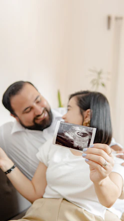 a man and a woman laying on a bed with a picture of their baby