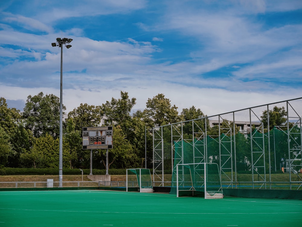 a green tennis court with a basketball hoop in the background