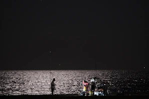 A group of club members proudly holding their fishing rods by the lake at sunrise.
