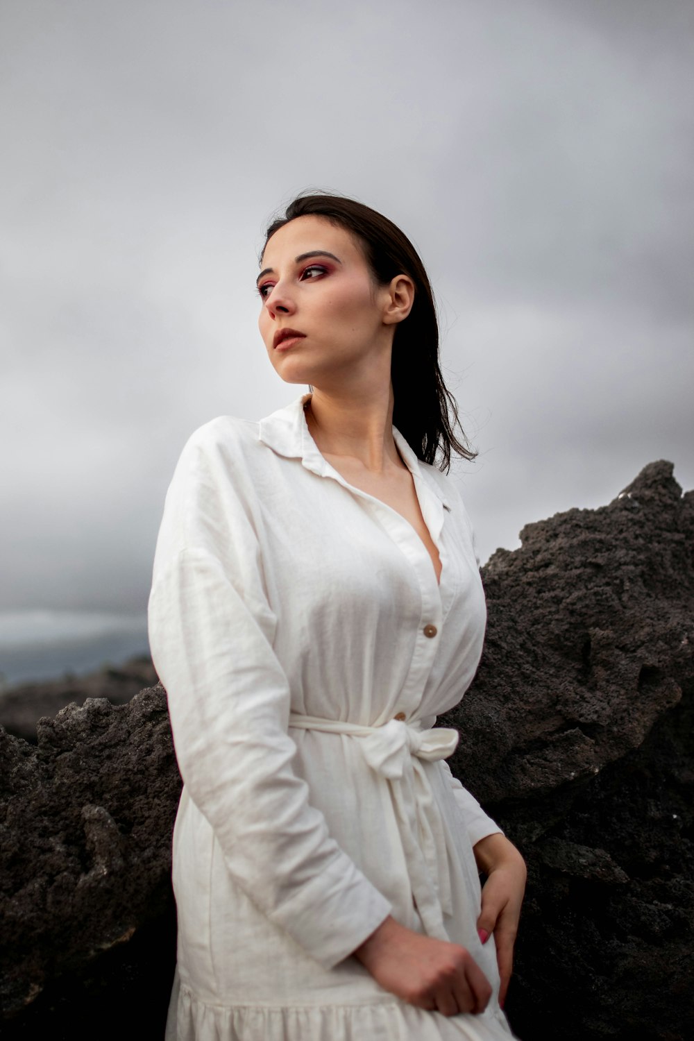 Une femme en robe blanche debout sur un rocher