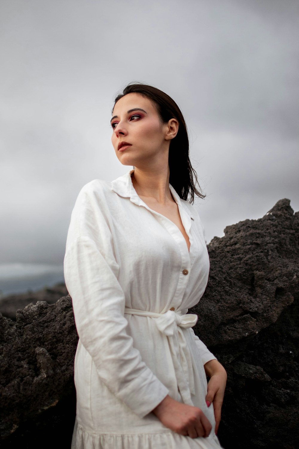 a woman in a white dress standing on a rock