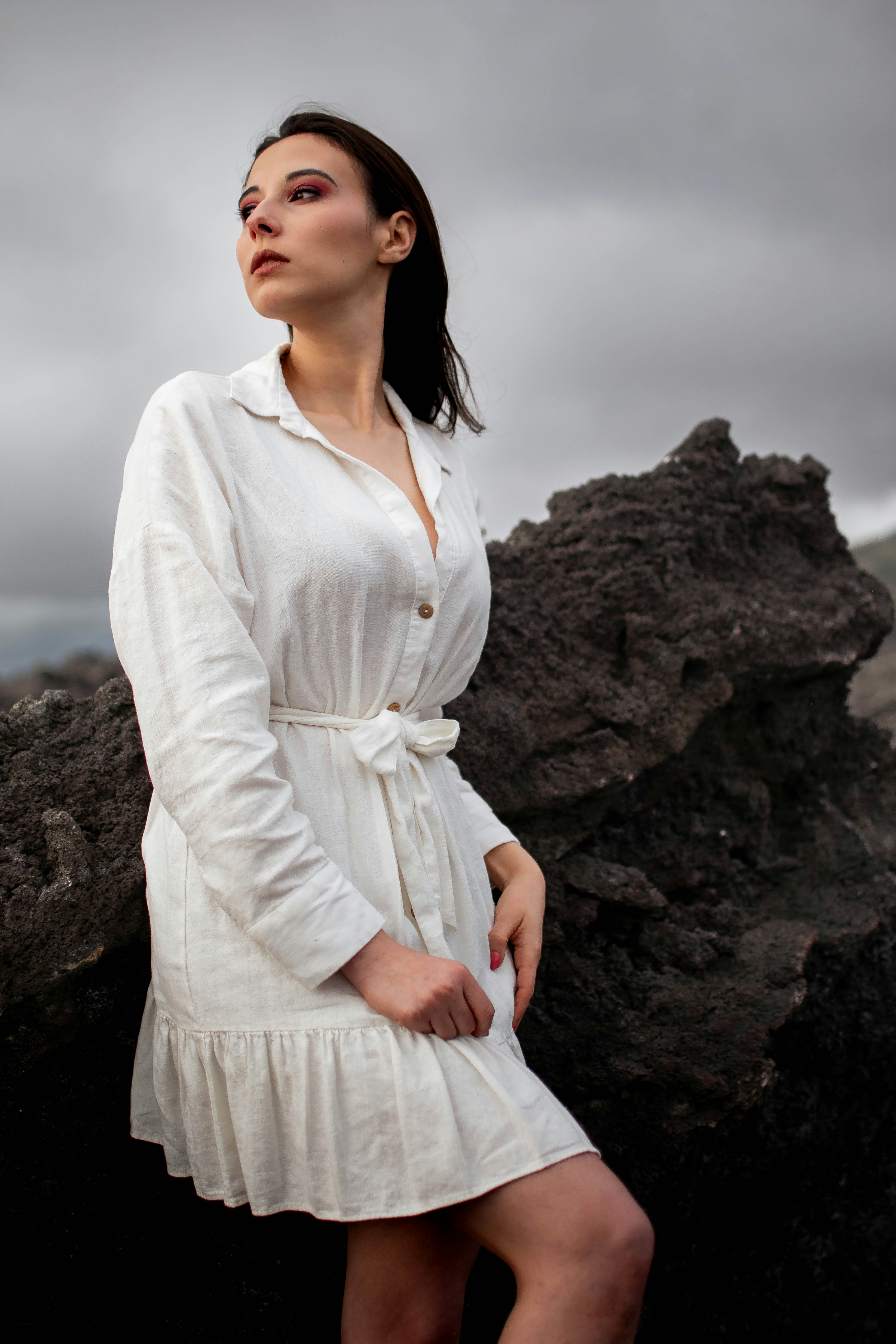 a woman in a white dress standing on a rock