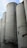 Tall, cylindrical concrete silos are lined up against a partly cloudy sky. Metal walkways and fixtures are attached to the structures, contributing to an industrial appearance.