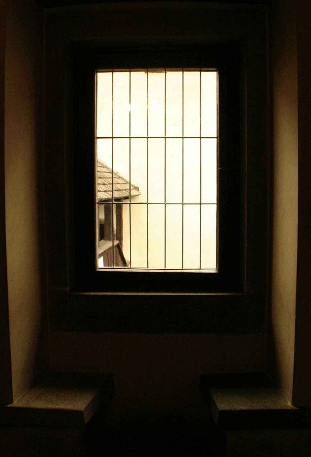 ein Fenster in einer Wand mit Blick auf ein Haus