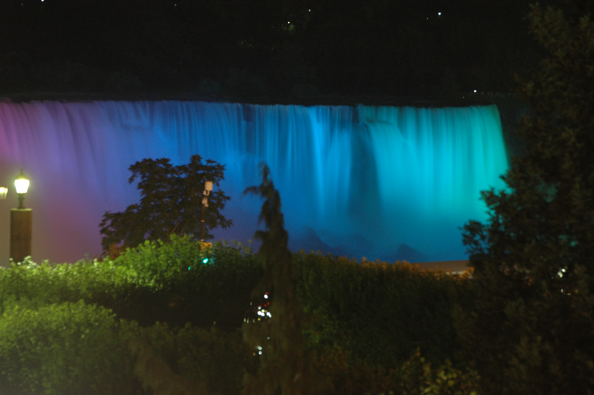 An evening shot of a multi-tiered waterfall illuminated by soft, warm lights, creating a tranquil ambiance.