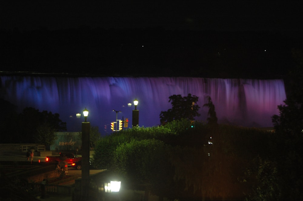 a car driving past a large waterfall at night