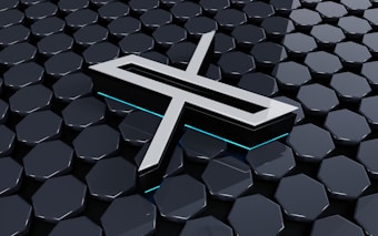 A metallic three-dimensional logo is positioned above a hexagonal tiled surface. The tiles have a glossy finish with a reflective appearance, and the logo features sharp lines and edges, with a futuristic design. Subtle neon blue lighting adds depth and contrast to the composition.