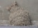 A textured, irregular mass resembling hardened clay or mud is adhered to a concrete wall. The mass consists of numerous small, rounded clumps tightly packed together, creating a rugged, rocky appearance.