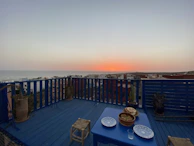 Sunset view from a balcony overlooking a serene cityscape, framed by gold railings.