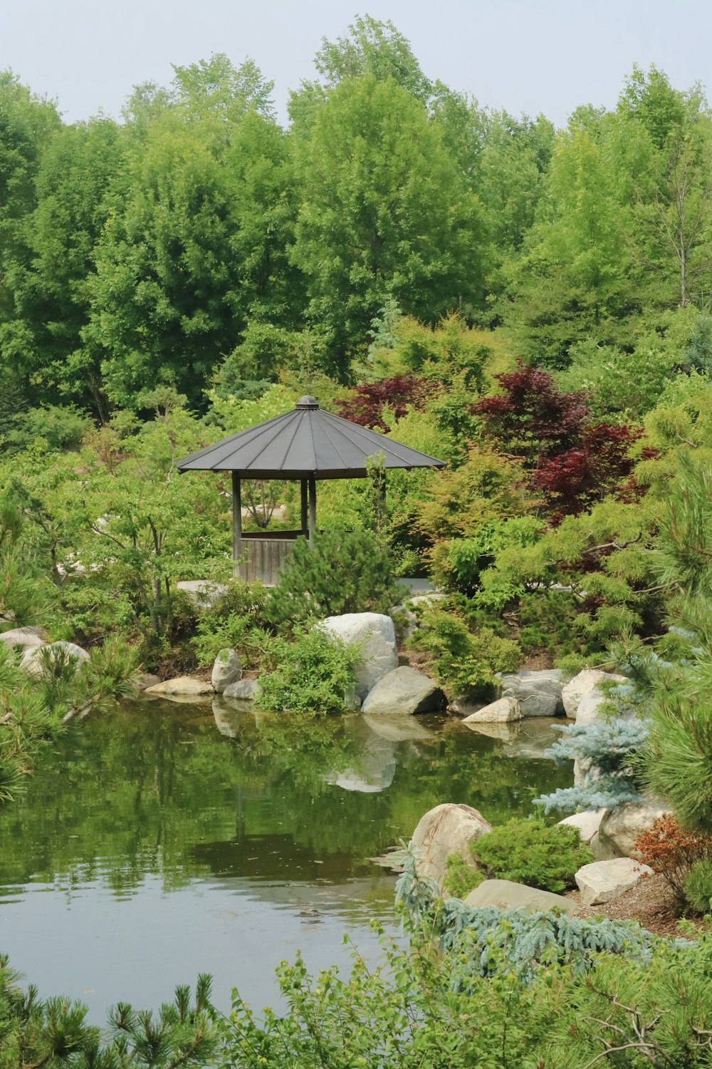 a gazebo in the middle of a pond surrounded by trees