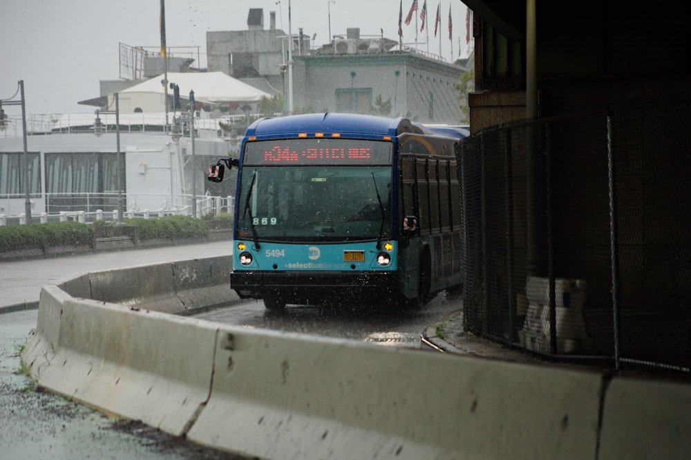 a blue bus driving down a rain soaked street