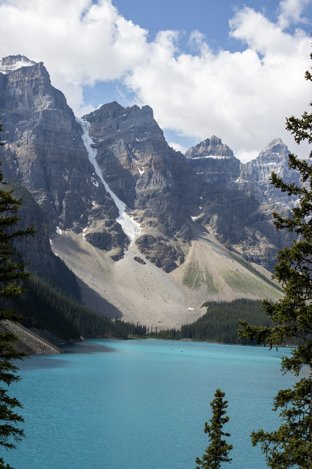 a lake surrounded by trees and mountains under a cloudy sky