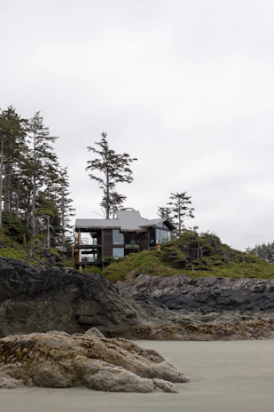 A sleek modern coastal house with glass facades and a green living roof overlooking the Scottish sea.