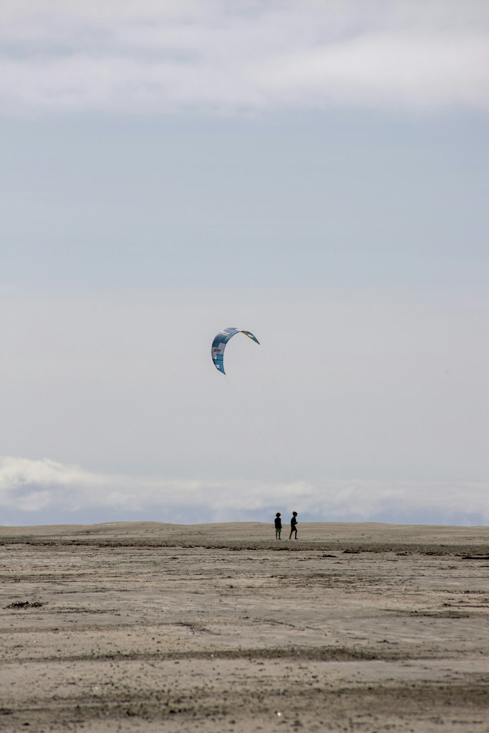 a couple of people standing on top of a sandy beach